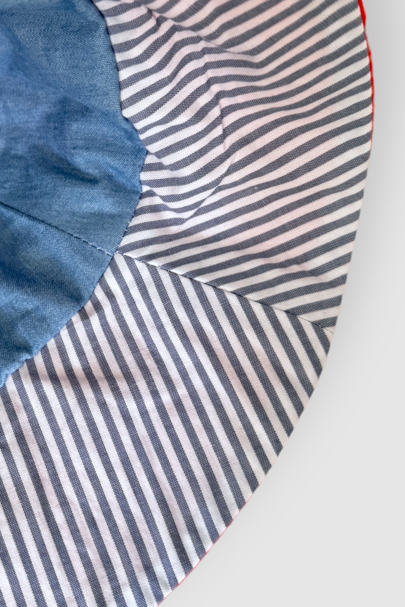 Introducing our versatile summer hat in deep orange denim featuring a stylish combination of white and navy striped cotton. The slim tie on the back allows for adjustable sizing, ensuring a perfect fit. Embrace the warmth of the sun while looking effortlessly chic.  DETAILS AND CARE  Fabric - denim 100% cottoton, &nbsp;70% Ramie 30% cotton  Hand wash