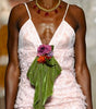 A model walks the runway wearing a light pink ruffled spaghetti-strap dress with sheer wide-leg tulle pants and a green leaf accent at the waist.