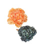 Two floral hair accessories, one orange and one green, on a white background.