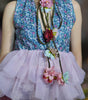Person wearing a floral top and pink skirt with decorative flowers on a blurred background