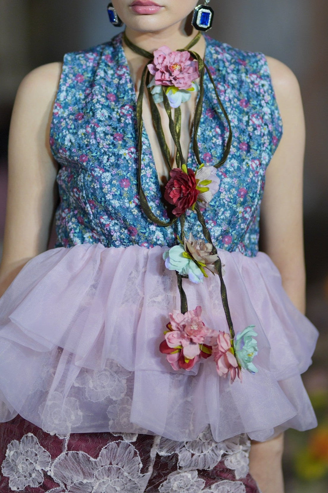 Person wearing a floral top and pink skirt with decorative flowers on a blurred background