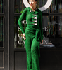 Woman in a green outfit standing in front of a store with large circular decorations.