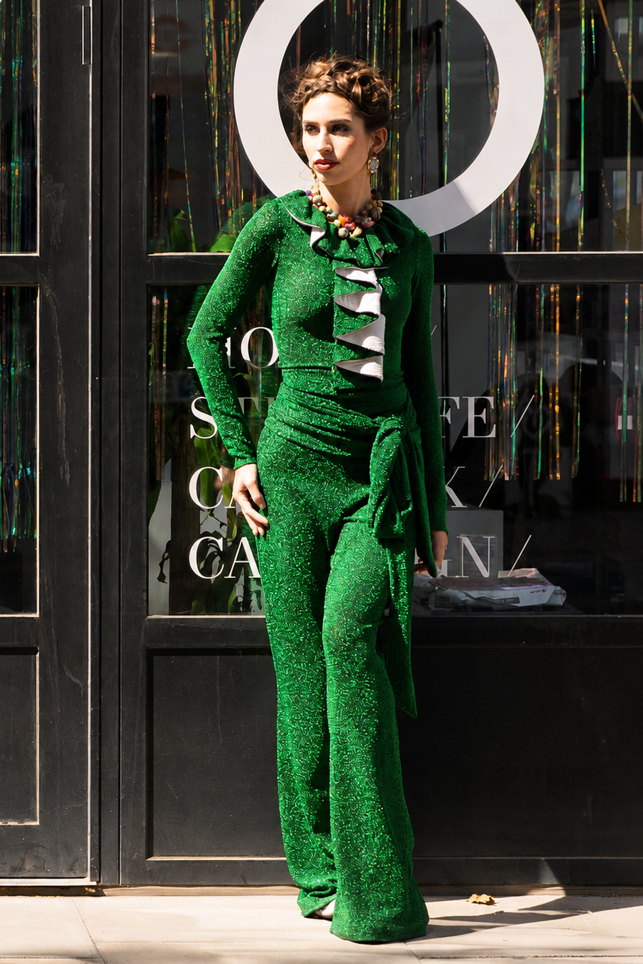 Woman in a green outfit standing in front of a store with large circular decorations.