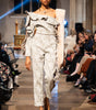 Model walking on a fashion show runway wearing a stylish outfit.
