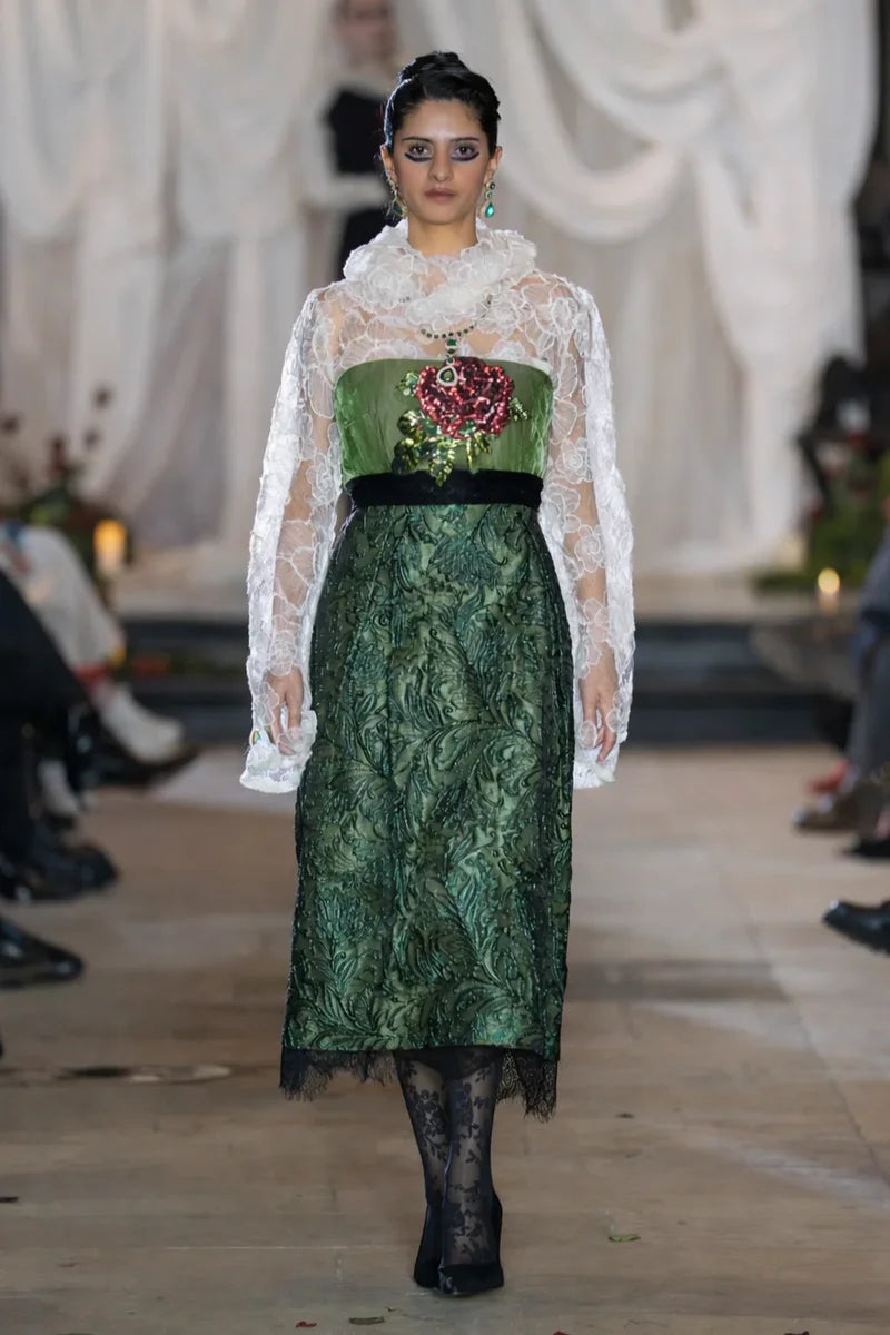 Model wearing a green dress with floral details on a runway