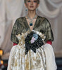 Model wearing a long, elegant dress with gold and white patterns on a runway.