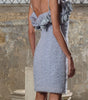Woman wearing a light blue dress with floral details in an indoor setting.