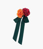 Floral accessory with orange and red flowers and a green bow on a white background