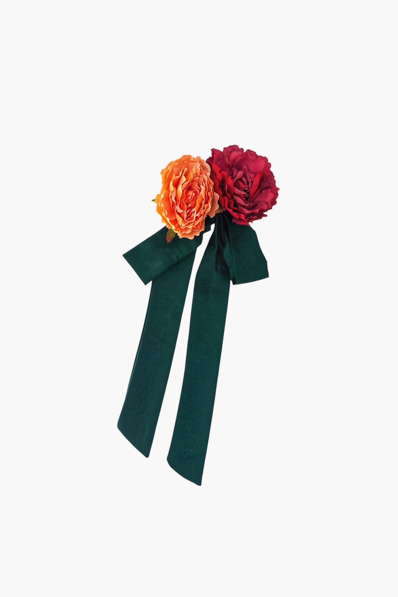 Floral accessory with orange and red flowers and a green bow on a white background