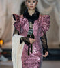 Model wearing a pink sequin dress with ruffled details on a runway.