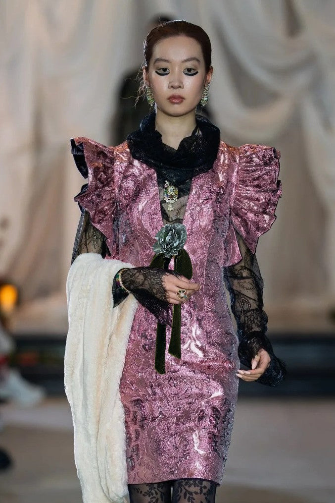 Model wearing a pink sequin dress with ruffled details on a runway.