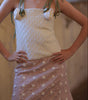Model wearing a white textured top and polka dot skirt in an indoor setting