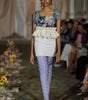 Model walking on a runway wearing a colorful outfit with floral patterns.